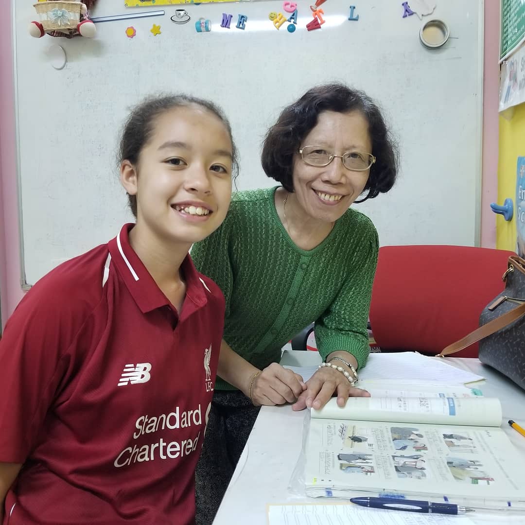 Student and teacher smiling together over a textbook